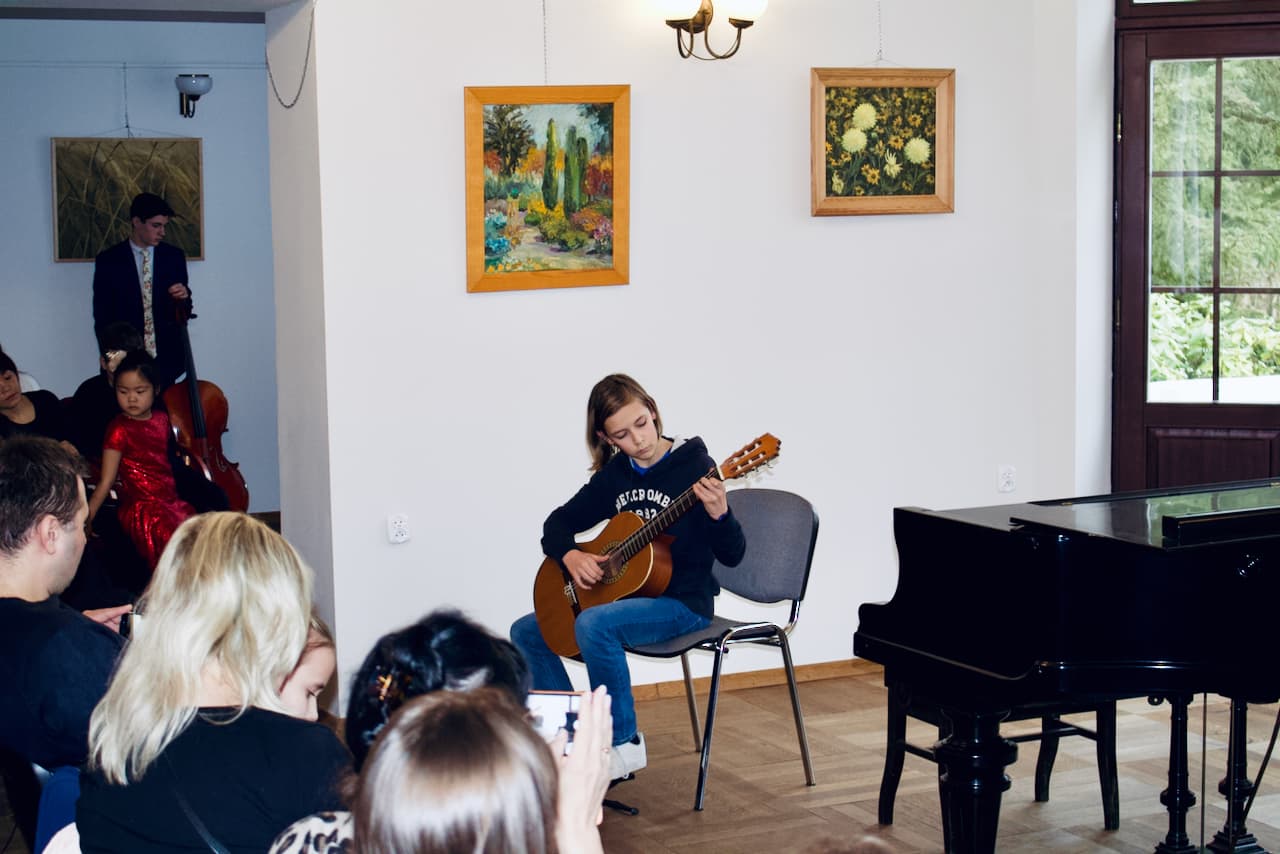 Uczeń Szkoły Muzycznej Unisono gra na gitarze klasycznej podczas koncertu w Pałacu Szustra w Warszawie